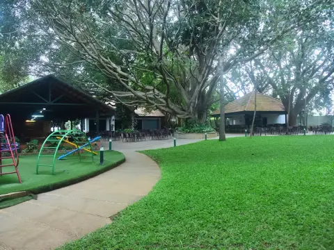 K. C. Palace Club clubhouse, garden lawn and children’s play area beneath a large tree