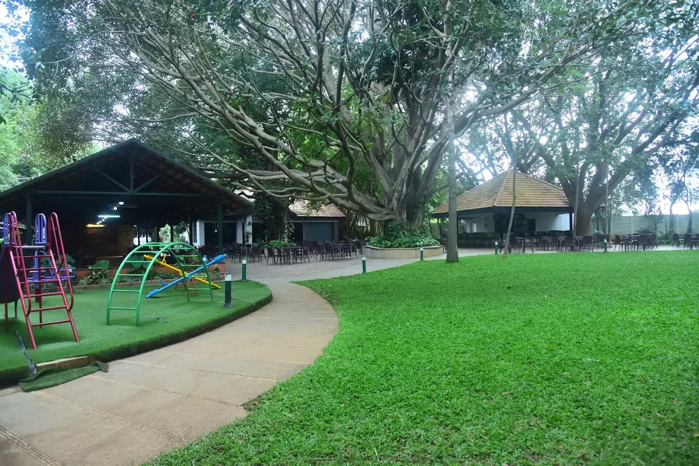 K. C. Palace Club clubhouse, garden lawn and children’s play area beneath a large tree